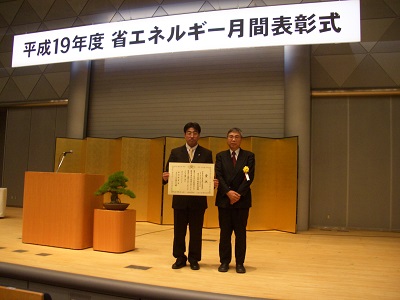 Ｈ１９　省エネルギー月刊表彰式の様子(壇上で2名が賞状を受取り記念撮影している)写真