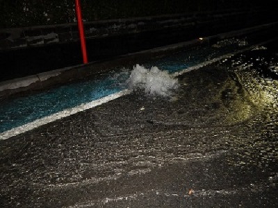 10/13未明、下水・雨水合流器行の道路のマンホールから水があふれる様子の写真